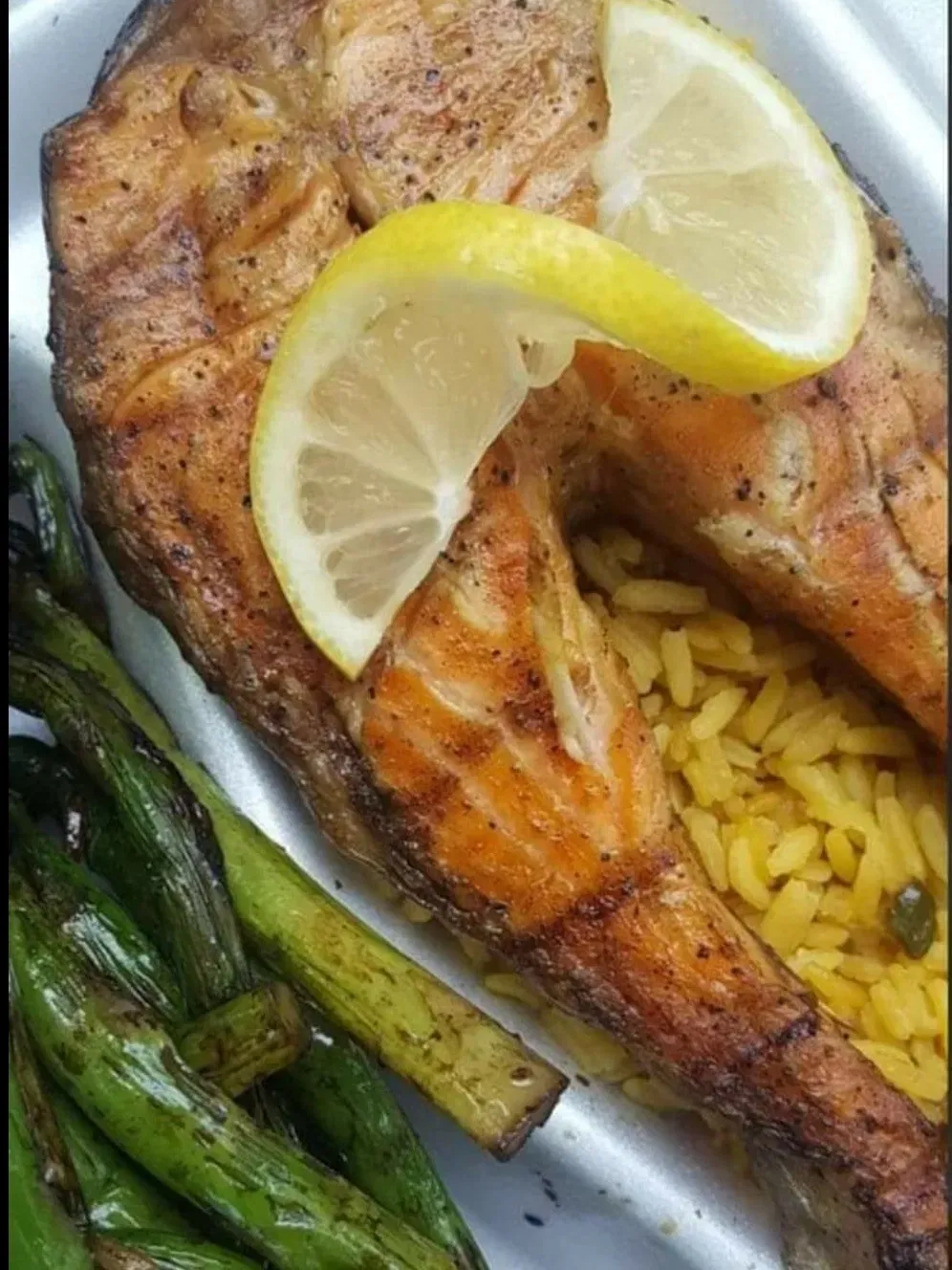 Grilled salmon entree with seasoned rice, lemon and green onions